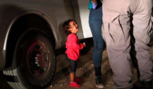Una niña mirando a un oficial estadounidense tras ser separada de su familia en la frontera