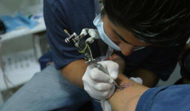 Un tatuador con unos de sus clientes, en Bogotá