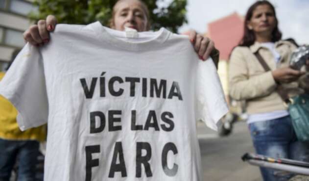 Una mujer sostiene una camiseta con la leyenda "Víctima de las Farc" durante una protesta afuera en la sede de la Jurisdicción Especial para la Paz (JEP) en Bogotá, el 13 de julio de 2018.