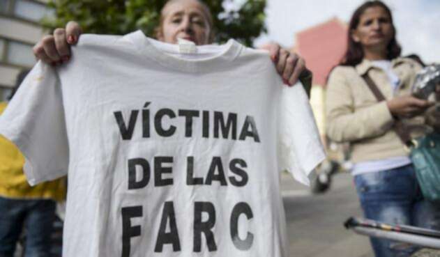 Una mujer sostiene una camiseta con la leyenda "Víctima de las Farc" durante una protesta afuera en la sede de la Jurisdicción Especial para la Paz (JEP) en Bogotá, el 13 de julio de 2018.