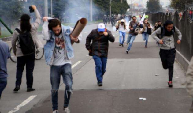 Varios estudiantes escapan de las bombas de aturdimiento del ESMAD
