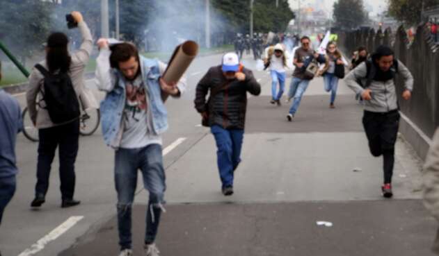 Varios estudiantes escapan de las bombas de aturdimiento del ESMAD