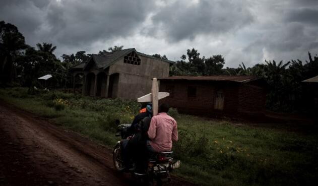 Tres congoleños montan una motocicleta y llevan una cruz por una tumba a lo largo de la carretera que une Mangina con Beni el 23 de agosto de 2018 en Mangina, en la provincia de Kivu Norte. Según informaron las autoridades, sesenta y una personas murieron en el último brote de ébola en la República Democrática del Congo (RDC), y agregaron que se habían agregado cuatro nuevos medicamentos a la lista de tratamientos.