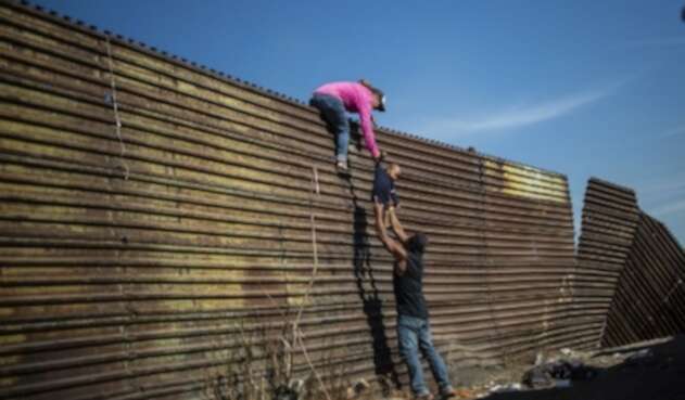 Inmigrantes en frontera de EE.UU. Un grupo de migrantes centroamericanos trepó la valla fronteriza entre México y Estados Unidos, cerca del cruce fronterizo de El Chaparral, en Tijuana, estado de Baja California, México, el 25 de noviembre de 2018. Cientos de migrantes intentaron asaltar una valla fronteriza que separa a México de El domingo, EE.UU., en medio de crecientes temores, permanecerán en México mientras se procesan sus solicitudes de asilo.