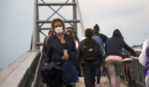 Mujer cruza puente peatonal con tapabocas Mujer cruza puente peatonal con tapabocas