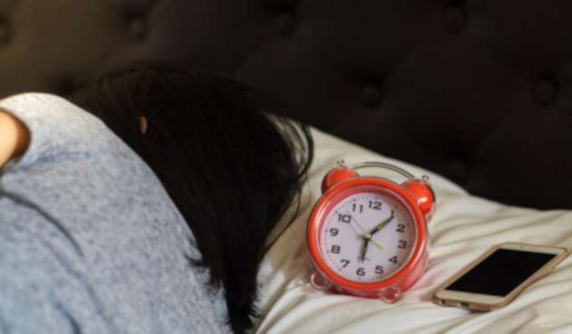 Una mujer trata de dormir, pero no deja lejos su teléfono celular