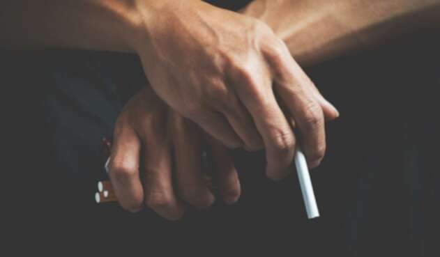 Un hombre sostiene cigarrillos en sus manos