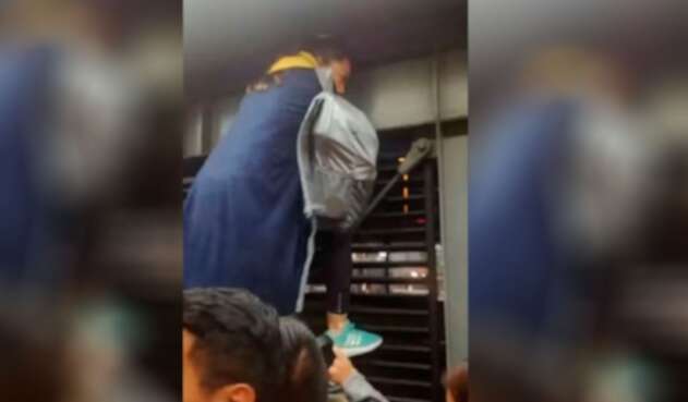 Mujer trepa reja en estación de Transmilenio Mujer araña en estación de Transmilenio