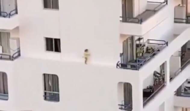 Niña caminando por el estrecho borde de un edificio