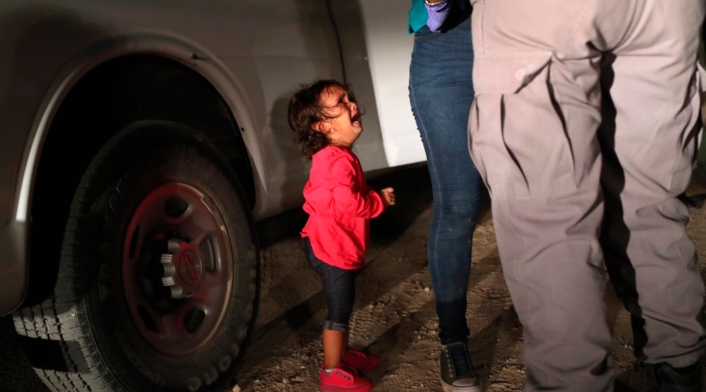Una niña mirando a un oficial estadounidense tras ser separada de su familia en la frontera