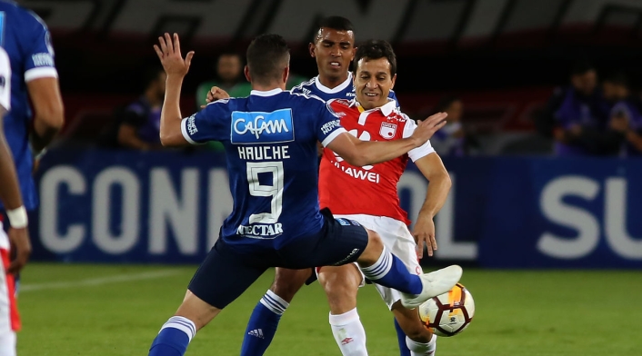 Diego Güastavino (Santa Fe) ante la marca de dos jugadores de Millonarios