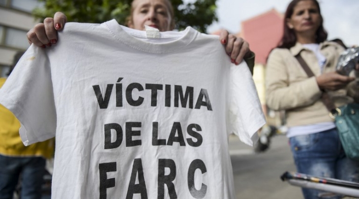 Una mujer sostiene una camiseta con la leyenda "Víctima de las Farc" durante una protesta afuera en la sede de la Jurisdicción Especial para la Paz (JEP) en Bogotá, el 13 de julio de 2018.