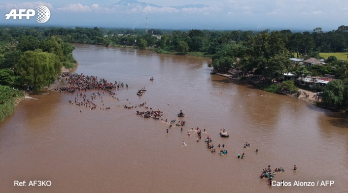 La caravana de migrantes cruza a pie el río que separa Guatemala de México.