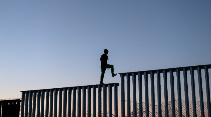 Migrantes en el muro entre México y Estados Unidos