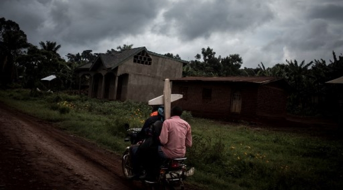 Tres congoleños montan una motocicleta y llevan una cruz por una tumba a lo largo de la carretera que une Mangina con Beni el 23 de agosto de 2018 en Mangina, en la provincia de Kivu Norte. Según informaron las autoridades, sesenta y una personas murieron en el último brote de ébola en la República Democrática del Congo (RDC), y agregaron que se habían agregado cuatro nuevos medicamentos a la lista de tratamientos.
