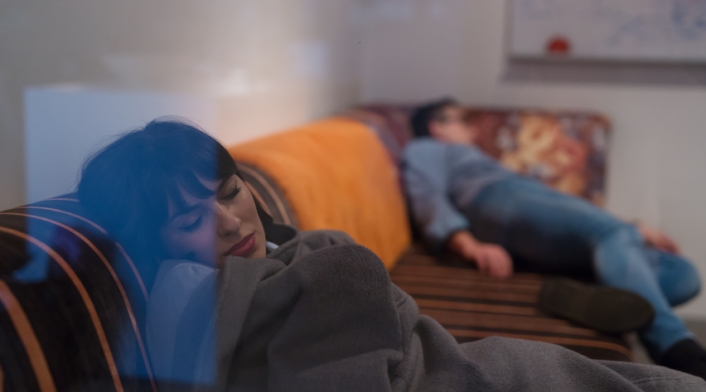 Una pareja tratando de dormir en un sofá