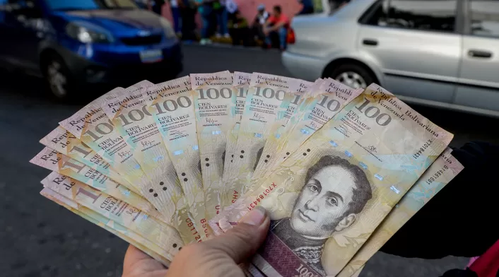 Un ciudadano venezolano expone bolívares, moneda oficial, en las calles de Caracas