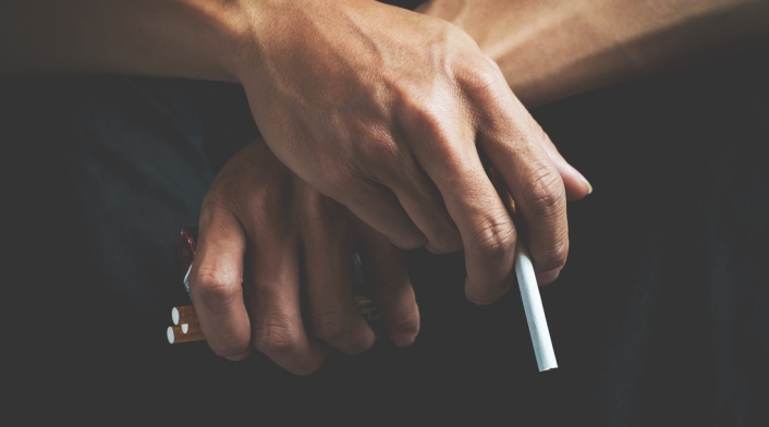 Un hombre sostiene cigarrillos en sus manos