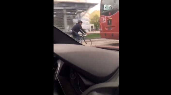 Biciusuario detrás de un articulado de Transmilenio