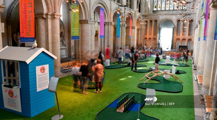 A donde normalmente se encuentran hileras de bancos, se ha desplegado una gran moqueta verde, de césped sintético, donde los clubes de golf acogen a los parroquianos.