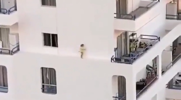 Niña caminando por el estrecho borde de un edificio
