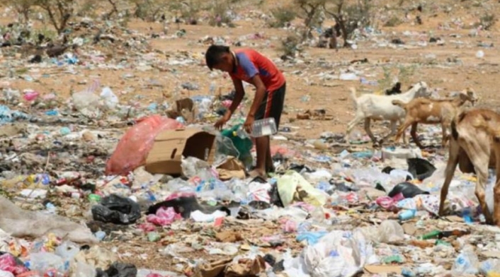 Niño indígena buscando alimentos entre la basura.