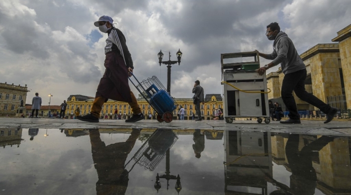 Vendedores ambulantes con tapabocas caminan en la plaza Bolívar, en Bogotá.