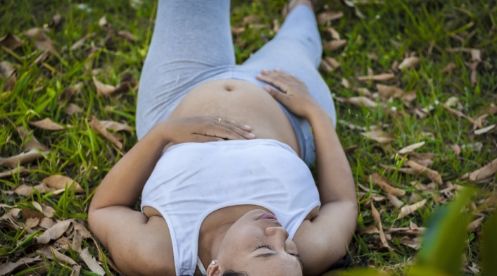 Mujer embarazada Mujer embarazada recostada en el pasto