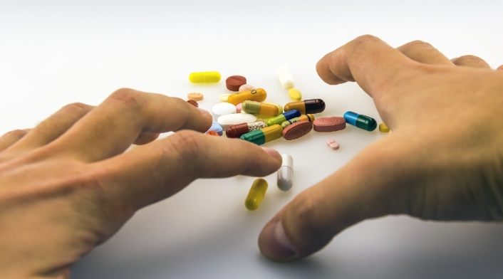 Las manos de un hombre queriendo agarrar varias pastillas