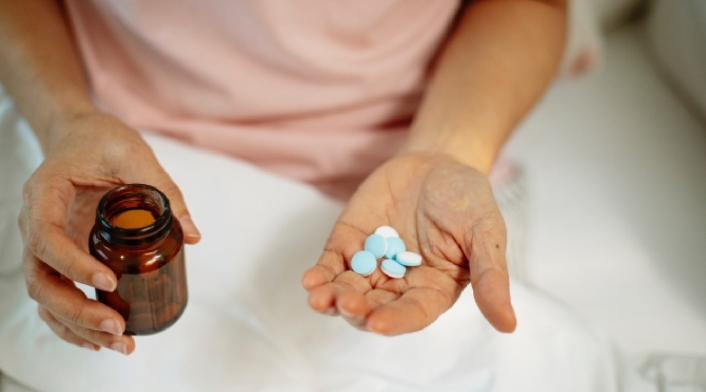 Una mujer con medicinas y un vaso de agua.
