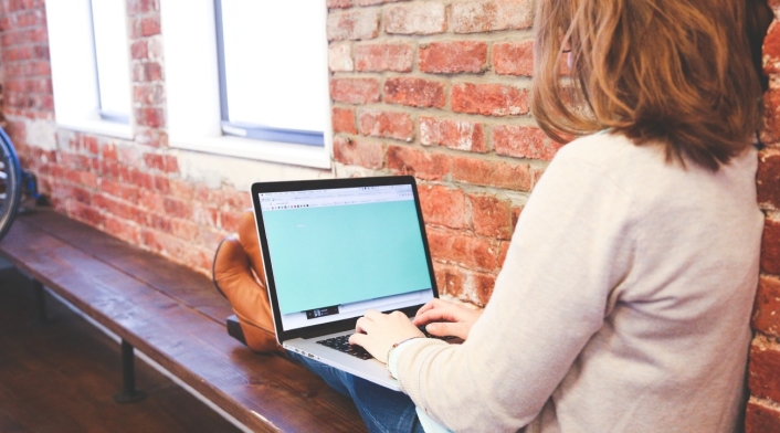 Mujer en un computador Mujer sentada y en sus piernas tiene un computador