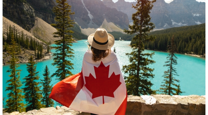 Empleo en Canadá para colombianos Mujer mirando la panorámica con bandera de Canadá