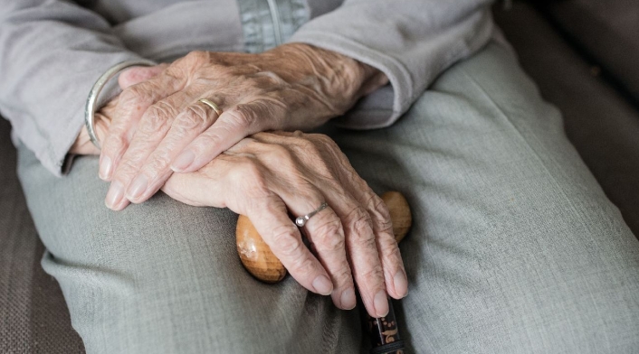 Manos de un anciano cruzadas y con un bastón
