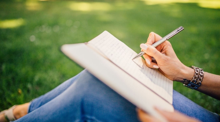 Mujer sentada escribiendo en el aire libre