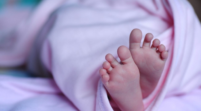 Pies de un bebé recién nacido envuelto en una cobija de color rosa
