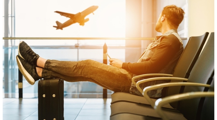 Tiquetes baratos en Colombia Hombre en aeropuerto esperando su vuelo