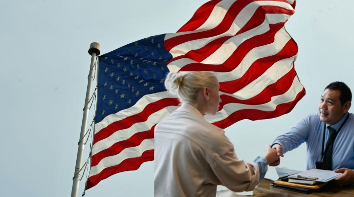 Trabajo en Embajada de Estados Unidos Bandera de Estados Unidos y dos personas