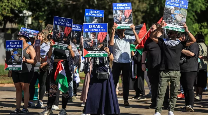 Activistas cantan y sostienen pancartas durante una manifestación frente a la embajada de Israel en Pretoria el 3 de octubre de 2025.