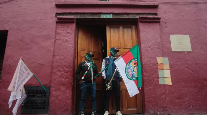 Dos integrantes de la Guardia Interétnica custodian la entrada del Ministerio de Vivienda en medio de las protestas del Congreso de los Pueblos en Bogotá.