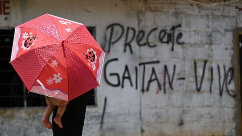 Un peatón pasa junto a una pared cubierta de grafitis de las Autodefensas Gaitanistas de Colombia, o Clan del Golfo, en Cáceres, Antioquia, Colombia, el 21 de marzo de 2023.