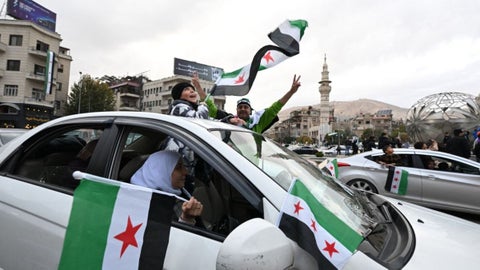 A lo largo de la mañana, columnas de personas llegaron al emblemático punto de encuentro en Damasco portando bengalas, pancartas y música entre los edificios.