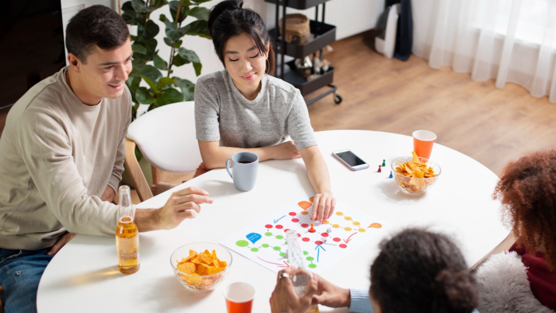 Un grupo de amigos reunidos alrededor de un juego de mesa durante el 1 de enero, una alternativa económica para compartir en casa.