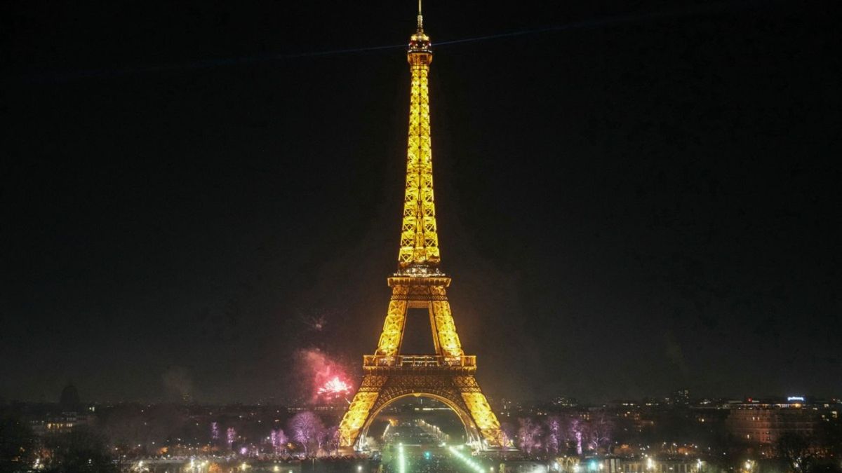 Los asistentes a la celebración se reúnen junto a la Torre Eiffel para dar la bienvenida al Año Nuevo, en el centro de París.