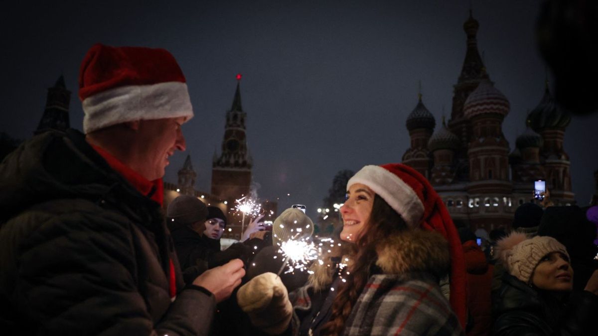 Asistentes a la celebración, con gorros de Santa Claus, se toman una selfi durante las celebraciones de la víspera de Año Nuevo en el borde de la Plaza Roja, en Moscú.