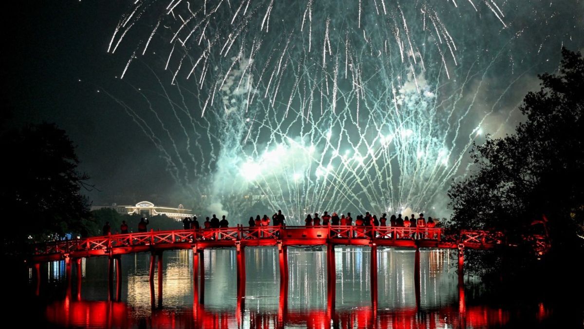 Los asistentes a la celebración observan los fuegos artificiales de la víspera de Año Nuevo desde el puente The Huc, en el lago Hoan Kiem, en Hanói.
