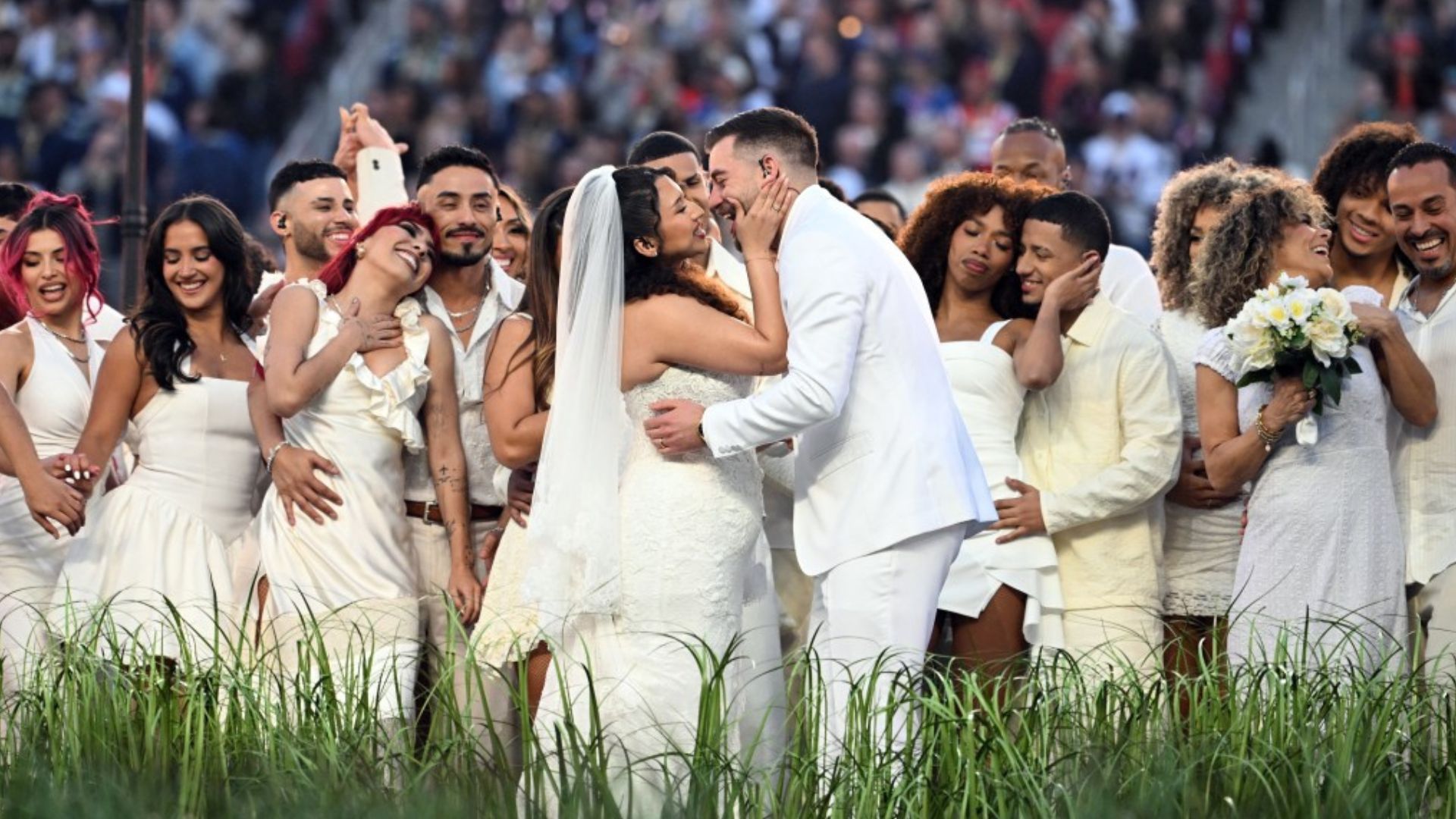 La pareja de novios estuvo cerca de un pastel de varios niveles mientras los artistas bailaban y se movían por el escenario.