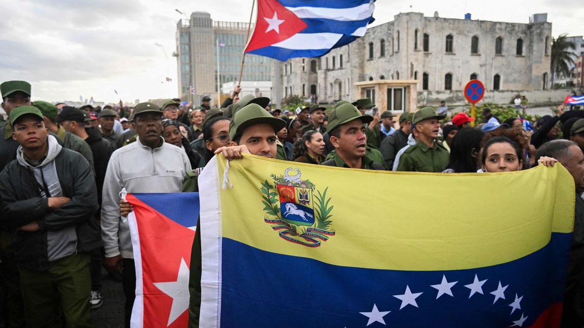 Miembros de las fuerzas armadas ondean banderas venezolanas y cubanas durante una protesta antiimperialista frente a la embajada de Estados Unidos en La Habana, el 16 de enero de 2026, contra la incursión estadounidense en Venezuela, donde 32 soldados cubanos perdieron la vida.