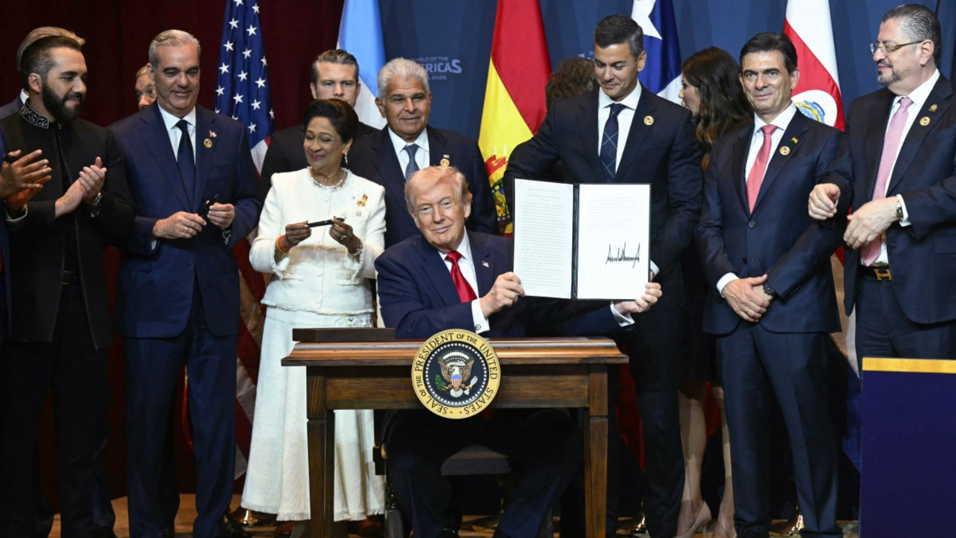 El presidente estadounidense Donald Trump muestra una proclamación recién firmada en la Cumbre 