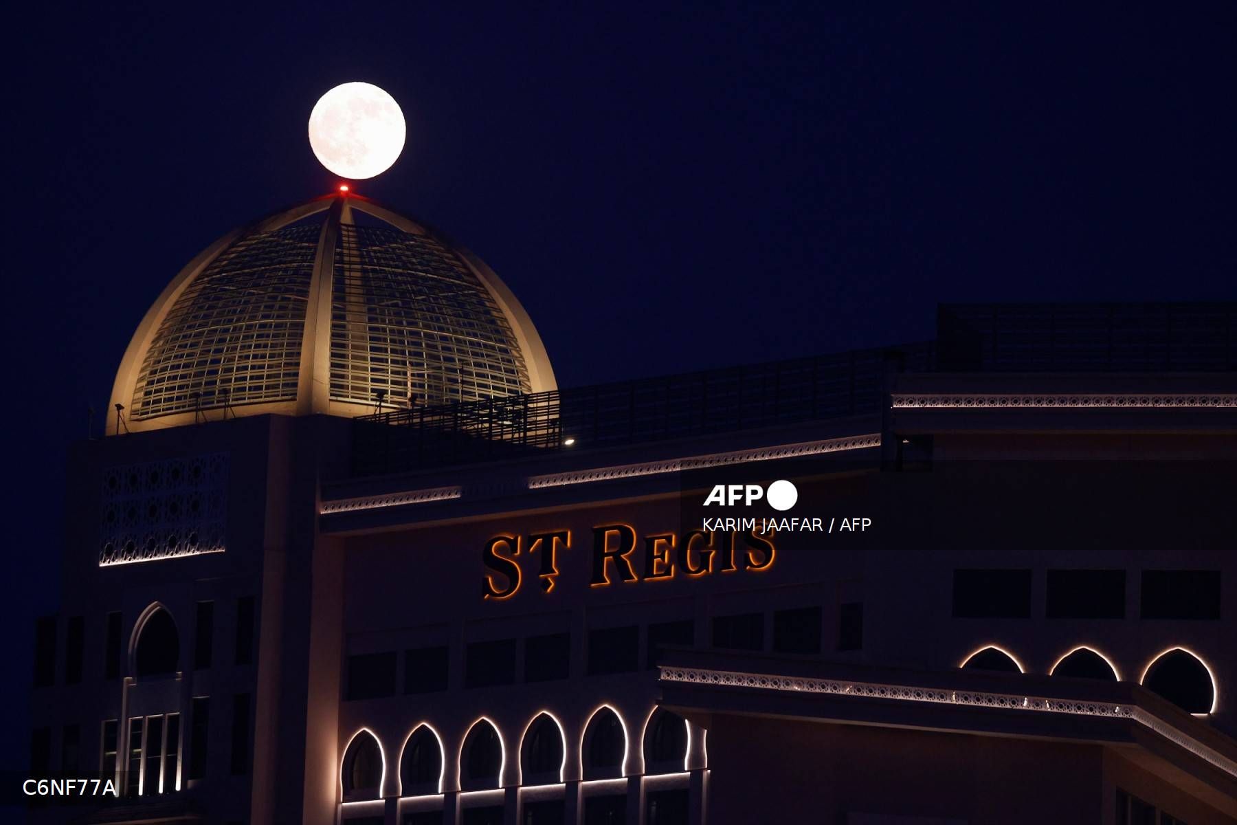 La luna llena sale detrás del hotel St. Regis en Doha.