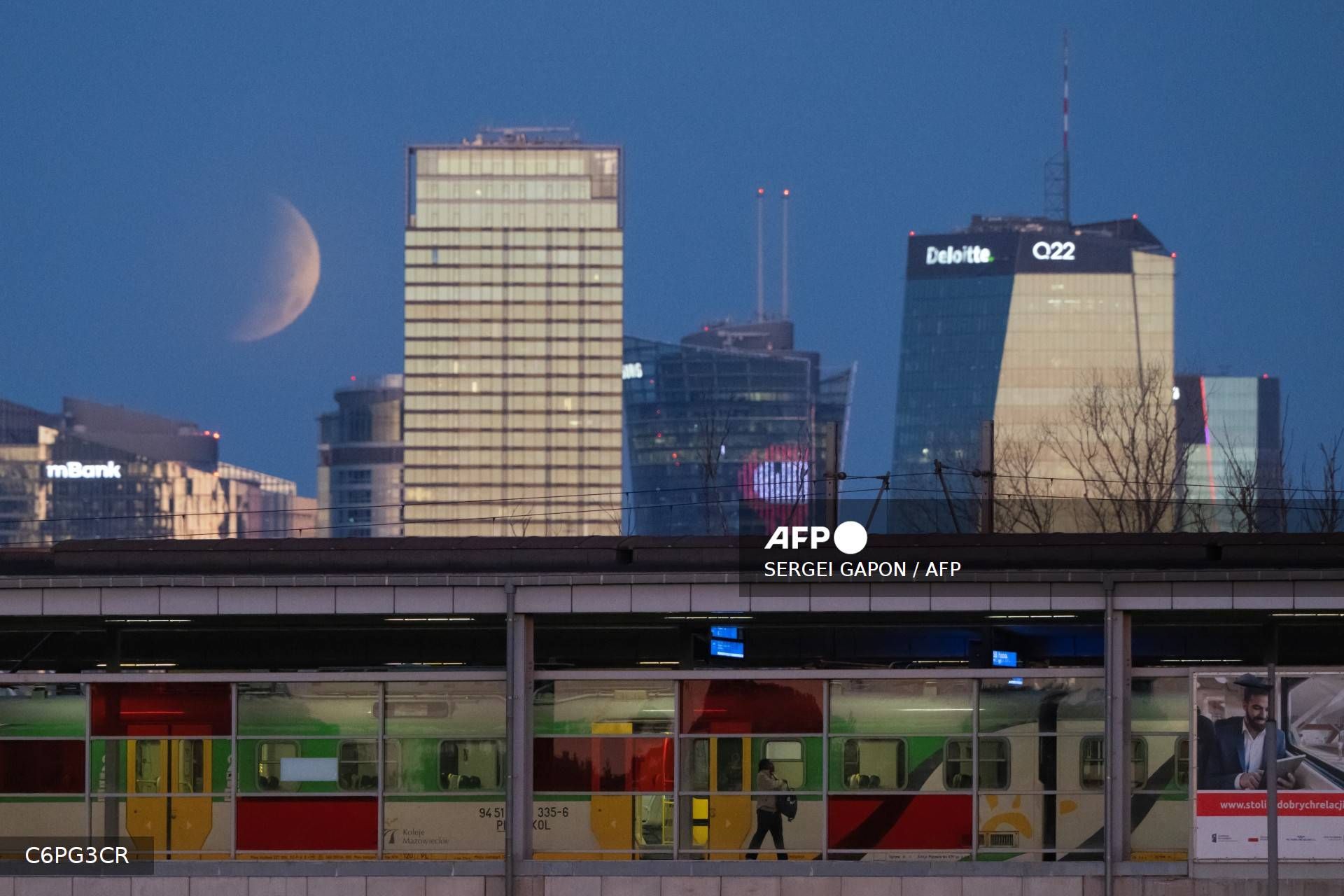 Un pasajero baja de un tren mientras la luna llena —también conocida como la «Luna del Esturión»— se oculta tras los rascacielos de Varsovia (Polonia) durante un eclipse lunar parcial.